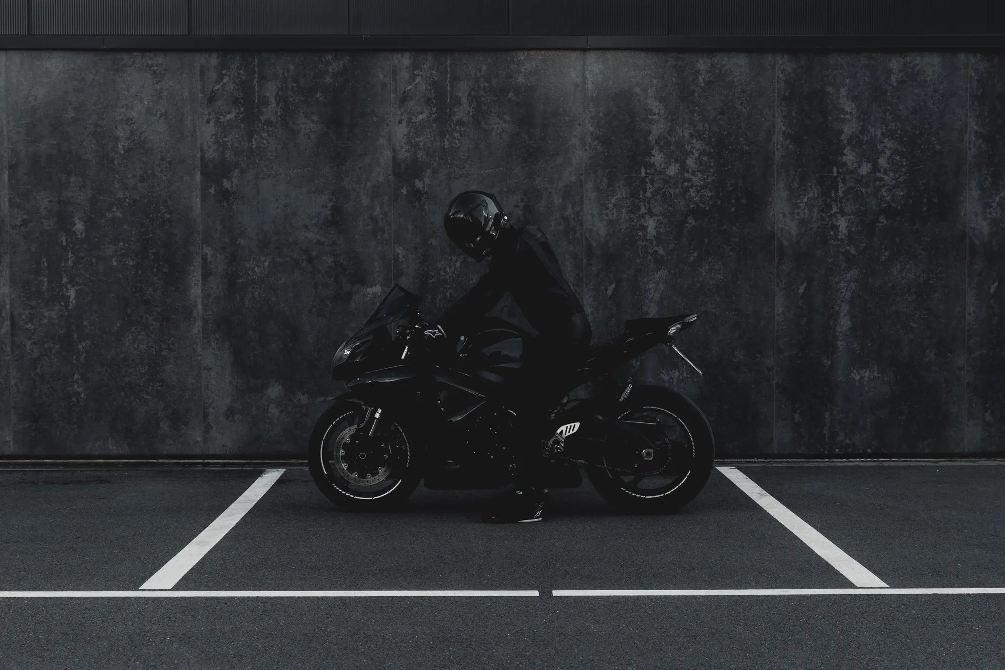 Eine Suzuki GSX-R 600 K8 steht vor einer dunklen Betonwand auf einer markierten Fläche.