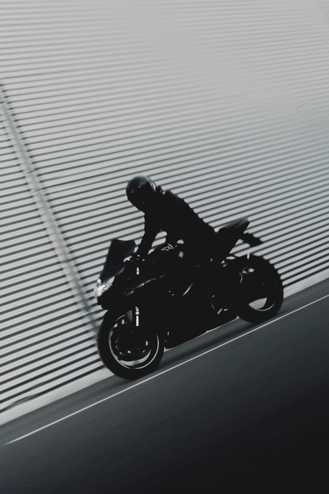 Eine Suzuki GSX-R 600 K8 in Fahrt vor einer geriffelten Wand, als Silhouette.