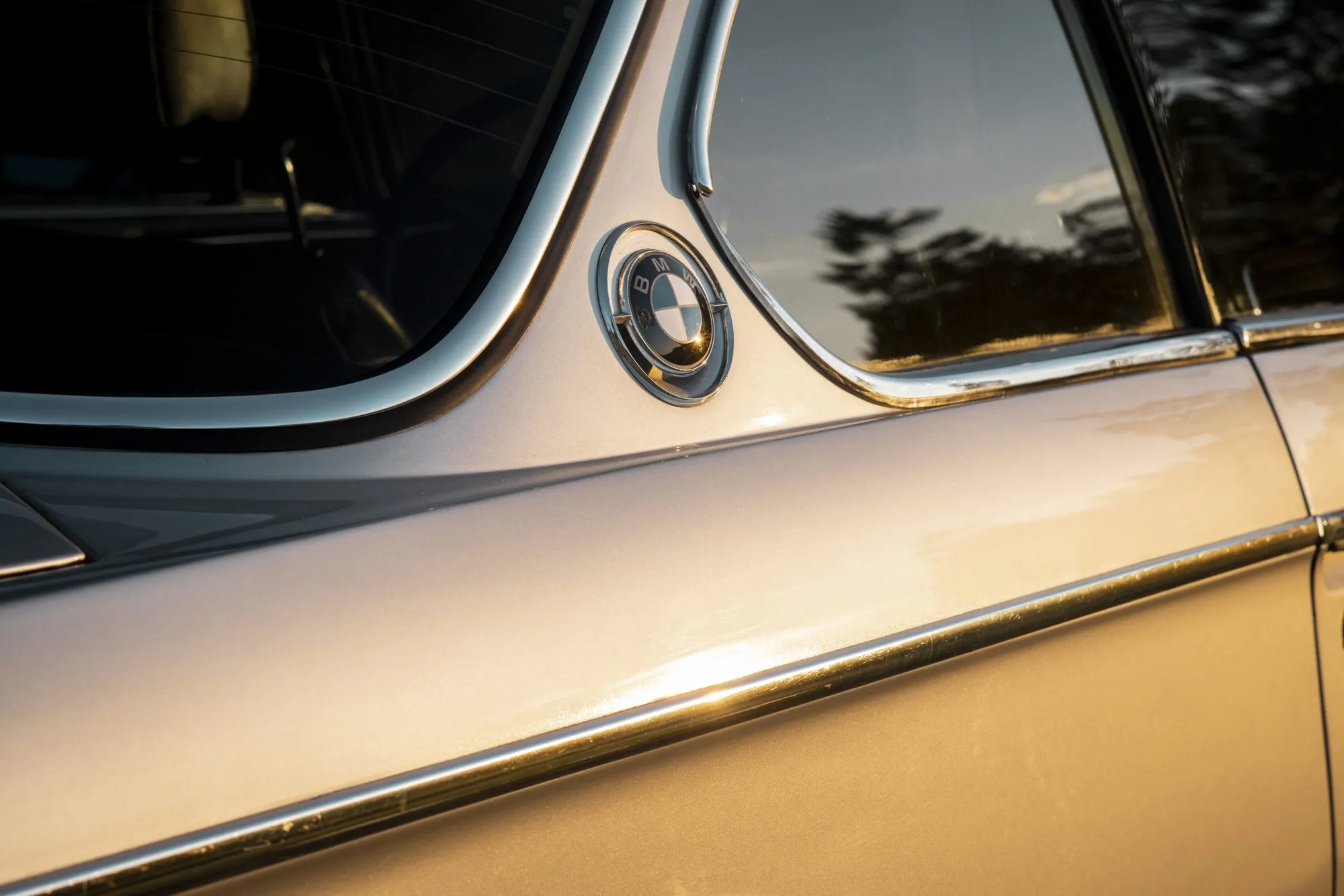Die Seite eines silbernen Coupés spiegelt das Abendlicht.
