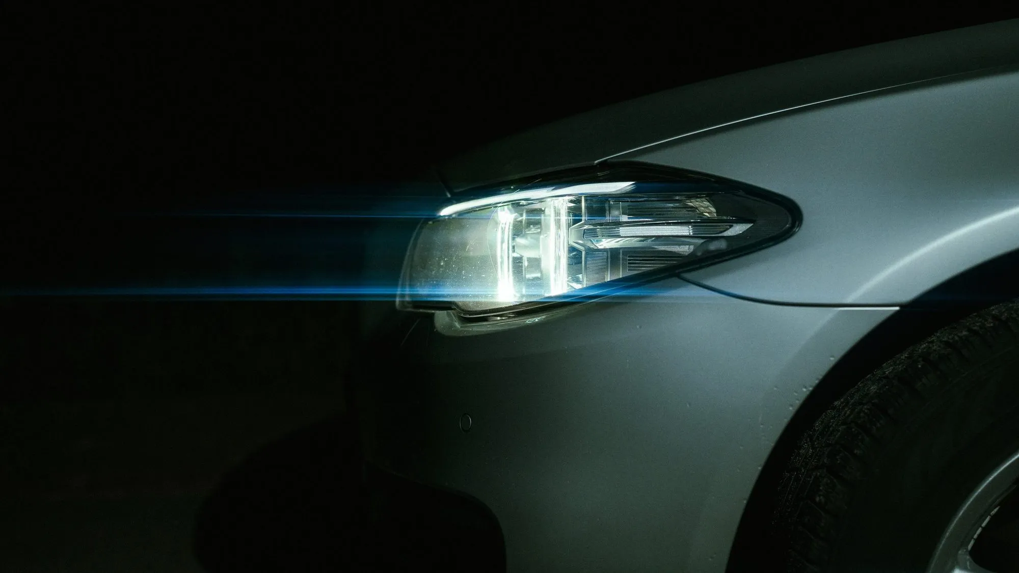 Ein Scheinwerfer im Dunkeln, daneben eine gezogene Lichtspur.
